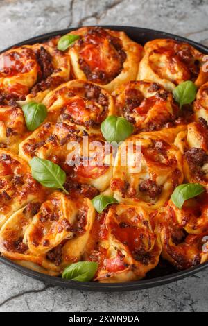 Cheesy Pepperoni Pizzeria Brötchen mit italienischen Würstchen, Mozzarella und Basilikum in der Nähe auf dem Bakong Gericht auf dem Tisch. Vertikal Stockfoto