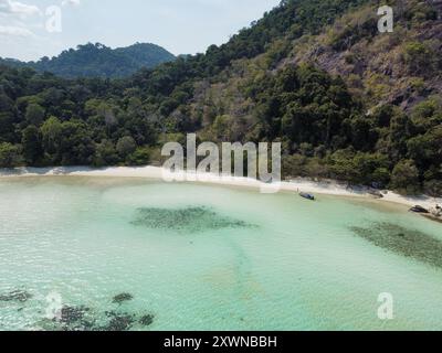 Blick aus der Vogelperspektive auf einen tropischen Strand in Koh Ra Wi mit weißem Sand, türkisfarbenem Wasser, Korallenriffen und dichter Vegetation Stockfoto