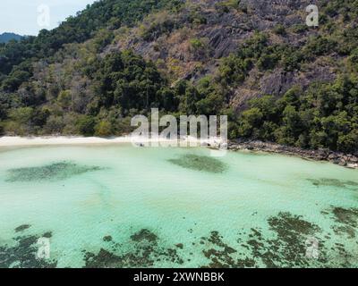 Aus der Vogelperspektive auf einen unberührten Strand auf Koh Ra Wi mit weißem Sand, türkisfarbenem Wasser, Korallenriffen und dichter Vegetation Stockfoto