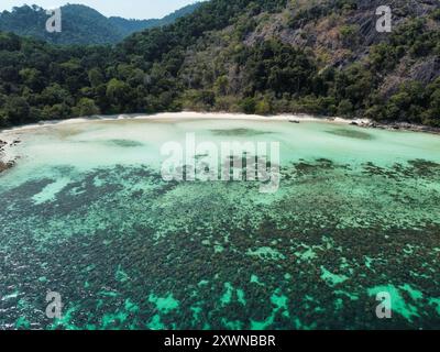 Blick aus der Vogelperspektive auf einen tropischen Strand in Koh Ra Wi mit weißem Sand, türkisfarbenem Wasser, Korallenriffen und dichter Vegetation Stockfoto