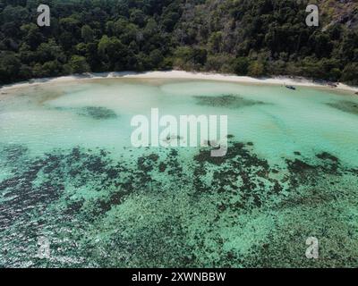 Aus der Vogelperspektive auf einen unberührten Strand auf Koh Ra Wi mit weißem Sand, türkisfarbenem Wasser, Korallenriffen und dichter Vegetation Stockfoto