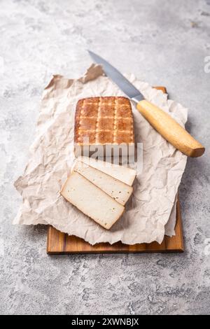 Geräucherter Bio-Tofu auf Küchentisch mit Messer Stockfoto