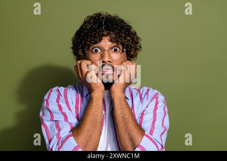 Portraitfoto des arabischen Geschäftsmannes tragen gestreiftes lässiges Hemd und Brillenbissen Nägel in Panik isoliert auf khakifarbenem Hintergrund Stockfoto