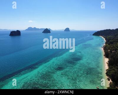 Blick aus der Vogelperspektive auf den Strand Ko Ngai mit seinem fantastischen Korallenriff und türkisfarbenem Wasser und anderen Trang-Inseln im Hintergrund Stockfoto