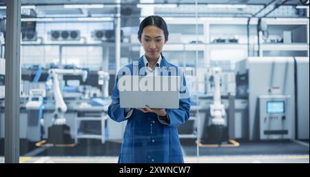 Porträt eines wunderschönen Ingenieurs der Elektronikindustrie, der lächelt und arbeitet. Junge asiatische Frau mit Laptop-Computer für Online-Forschung, Überwachung von industriellen künstlichen Intelligenzsystemen Stockfoto