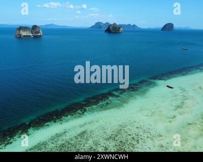 Blick aus der Vogelperspektive auf den Strand Ko Ngai mit seinem fantastischen Korallenriff und türkisfarbenem Wasser und anderen Trang-Inseln im Hintergrund Stockfoto