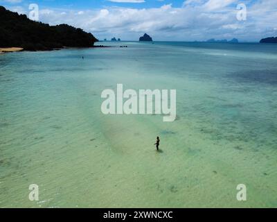 Blick aus der Vogelperspektive auf den Strand von Koh Kradan mit einem Reisenden, der die Korallenriffe der tropischen Insel an einem warmen und sonnigen Tag mit blauem Himmel erkundet Stockfoto