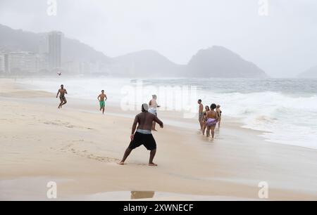 Die Leute genießen sich am Copacabana Beach trotz des trostlosen Wetters Stockfoto