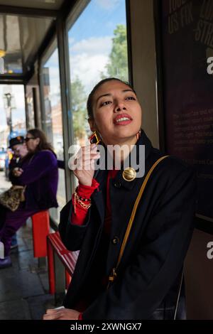 London - 06 11 2022: Mädchen an der Bushaltestelle berührt einen Ohrring Stockfoto