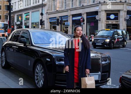 London - 06 11 2022: Mädchen hält nach dem Einkaufen vor einem Luxusauto an Stockfoto