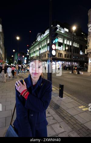 London - 06 11 2022: Mädchen berührt abends in der New Oxford Street ihre Schulter Stockfoto