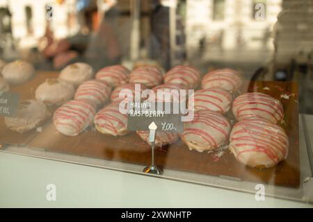 Desserts und Donut-Schautafel. Nahaufnahme einer Vielzahl von farbig glasierten Donuts auf einem Fenster eines Cafés in Krakau. Stockfoto