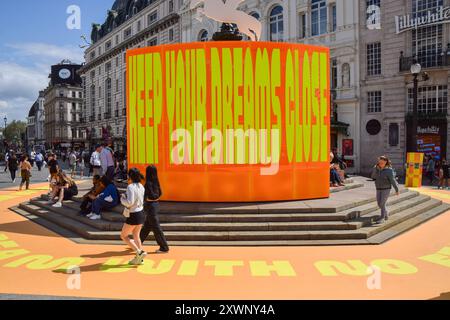 London, Großbritannien. August 2024. Die Leute spazieren an der neuen Kunstinstallation „Good Things Come That Who Wait“ von Yinka Ilori am Shaftesbury Memorial Fountain, im Volksmund Eros, im Piccadilly Circus vorbei. Quelle: SOPA Images Limited/Alamy Live News Stockfoto