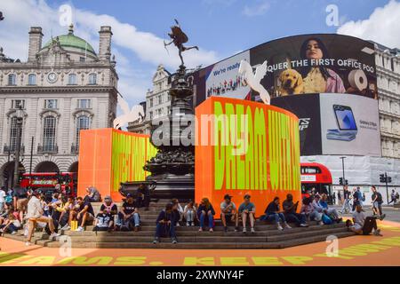 London, Großbritannien. August 2024. Neben der neuen Kunstinstallation „Good Things Come That Who Wait“ von Yinka Ilori sitzt man am Shaftesbury Memorial Fountain, im Volksmund Eros, im Piccadilly Circus. Quelle: SOPA Images Limited/Alamy Live News Stockfoto