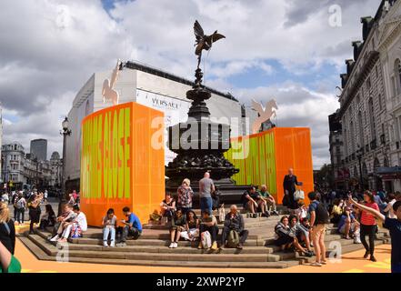 London, Großbritannien. August 2024. Neben der neuen Kunstinstallation „Good Things Come That Who Wait“ von Yinka Ilori sitzt man am Shaftesbury Memorial Fountain, im Volksmund Eros, im Piccadilly Circus. (Foto: Vuk Valcic/SOPA Images/SIPA USA) Credit: SIPA USA/Alamy Live News Stockfoto