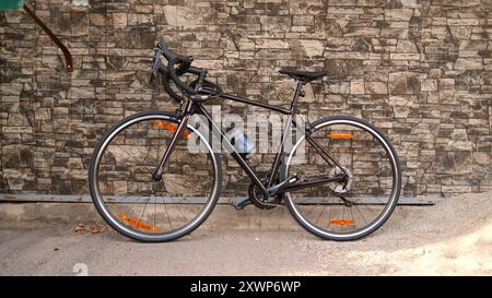 Rennrad gegen Steinmauer gelehnt. Rennrad parkte auf dem Bürgersteig. Städtisches Radfahren und umweltfreundliches Verkehrskonzept Stockfoto