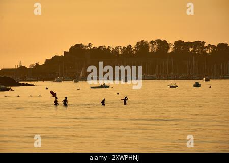 Während der Tag in die Nacht vergeht, schaffen die Silhouetten junger Menschen, die im Wasser des Ladeira Beach spielen und baden, ein fesselndes und nostalgisches erlebnis Stockfoto