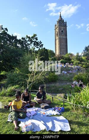 Warmer, sonniger Tag mit Familie und Freunden auf dem Gras unter dem Cabot Tower auf Brandon Hill, Bristol, Großbritannien. Der Cabot Tower wurde 1897 gebaut Stockfoto