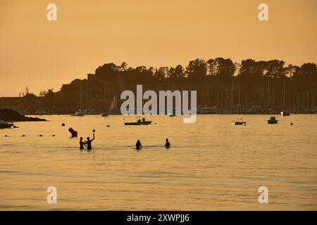 Während der Tag in die Nacht vergeht, schaffen die Silhouetten junger Menschen, die im Wasser des Ladeira Beach spielen und baden, ein fesselndes und nostalgisches erlebnis Stockfoto