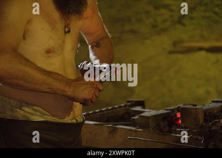 Schmiede-Schatten: Schmied arbeitet in einer düsteren Höhle Stockfoto