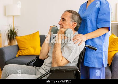 Alter Mann im Rollstuhltraining bei Physiotherapeuten mit Hanteln zu Hause. Stockfoto