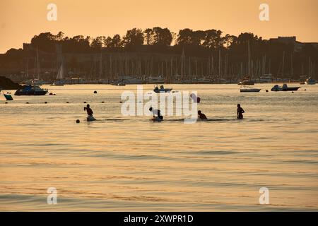 Während der Tag in die Nacht vergeht, schaffen die Silhouetten junger Menschen, die im Wasser des Ladeira Beach spielen und baden, ein fesselndes und nostalgisches erlebnis Stockfoto