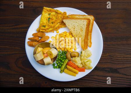 Englisches Frühstück mit pochierten Eiern, Speck, Würstchen, Obst, Brot, Marmelade, Butter, Tomaten, Gemüse Stockfoto