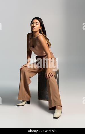 Eine stilvolle asiatische Frau in brauner Hose posiert selbstbewusst. Stockfoto