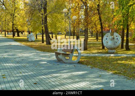 Eine Bank in einem sonnendurchfluteten Herbstpark Stockfoto