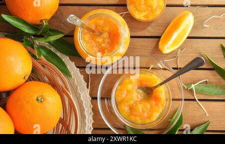 Hausgemachte Orangenmarmelade in Glasgläsern auf Holztisch mit Obststücken. Draufsicht. Stockfoto