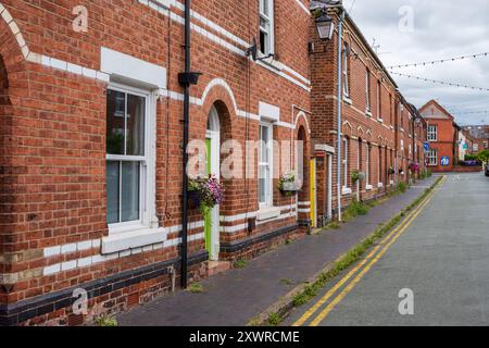 Charmante Backsteinhäuser mit Bogenfenstern und Blumenkästen in einer ruhigen Vorstadtstraße. Stockfoto