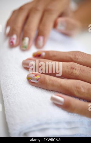 Bunte Nagelkunst auf Fingernägeln, die auf einem Handtuch liegen Stockfoto