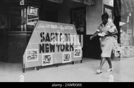 Eine Afroamerikanerin läuft 1938 an einer Werbeanzeige für den Film „Saint in New York“ vor dem Lyric Theater in Odessa, Texas, vorbei. Stockfoto