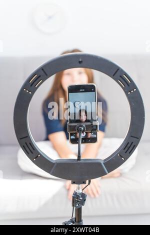 Kleines Mädchen vor Teenager Bloggerin vor Smartphone Kamera auf Lampe, wählte Fokus. Vertikales Foto. Hochwertige Fotos Stockfoto