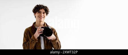Junger Fotograf Lächelt, Während Er Die Kamera Im Studio Hält Stockfoto
