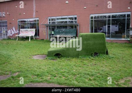 Ein grasbewachsenes Auto in einem Berliner Park dient als Metapher für Nachhaltigkeit und umweltfreundliches Leben. Dieses Bild zeigt die Mischung aus urbanem Leben und Natur und fördert umweltfreundliche Initiativen. Stockfoto