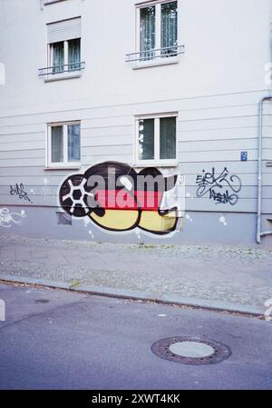 Street Art Wandgemälde mit einem Fußball und der deutschen Flagge an einer Wohnwand. Dieses Graffiti spiegelt den nationalen Stolz und die Leidenschaft für Fußball wider und fängt urbanen künstlerischen Ausdruck ein. Stockfoto