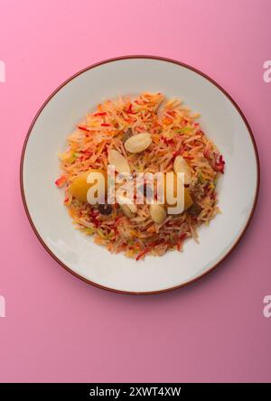 Farbenfroher Basmati-Reis auf einer weißen Platte mit rosa Hintergrund Stockfoto