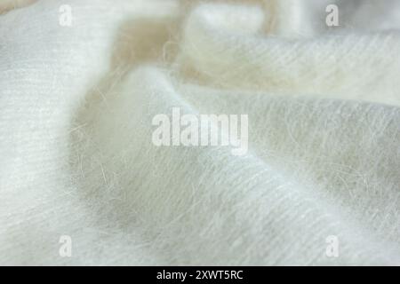 Nahaufnahme der Hintergrundstruktur aus weißem Strickgewebe aus Angora oder Wolle. Hintergrundtextur von Angora. Stockfoto