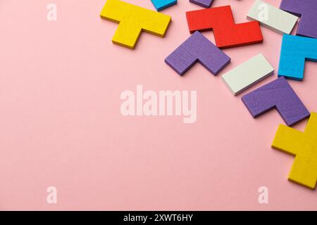 Bunte hölzerne Puzzleteile auf rosa Hintergrund. Leerzeichen für Text Stockfoto