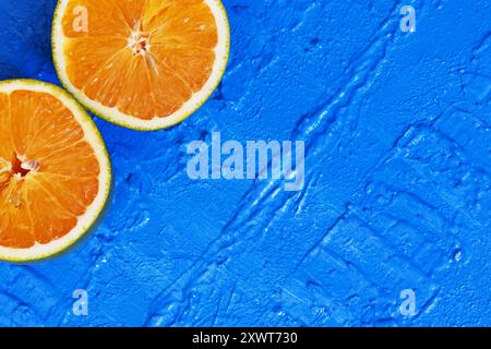 Zwei Teile einer Orange in diagonaler Position auf einem blauen Tisch. Stockfoto