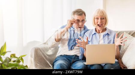 Überrascht reifes Paar gewinnen online Auktion, mit Laptop Stockfoto