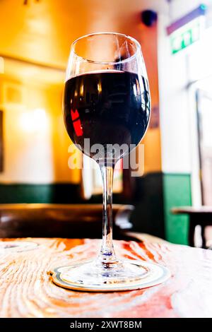 Großaufnahme eines Glases Rotwein auf Holztisch in einem gemütlichen britischen Pub Stockfoto