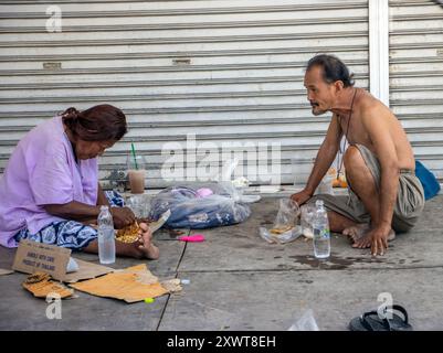 BANGKOK, THAILAND, 16. JUNI 2024, ein älteres armes Paar isst zusammen auf der Straße Stockfoto