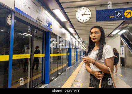 Eine junge Frau wartet auf einem unterirdischen Bahnsteig auf einen Zug Stockfoto