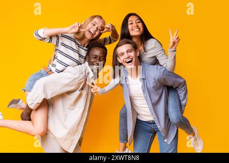 Zwei internationale Teenager-Paare haben Spaß über gelbem Hintergrund Stockfoto