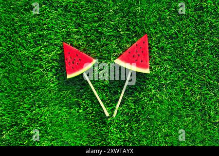 Sommerfrisches Bild von Lutscher oder eisförmiger Wassermelonenscheibe auf dem Grashintergrund Stockfoto