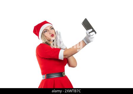 Junge blonde Latina-Frau verkleidet als weihnachtsmann, die einen Kuss auf Handy bläst, isoliert auf weißem Hintergrund Stockfoto