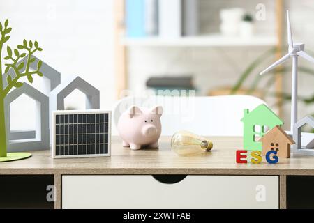 Windturbinenmodell mit Schweinebank, Glühbirne und Solarpanel auf Tisch im Büro. Konzept der grünen Energie Stockfoto