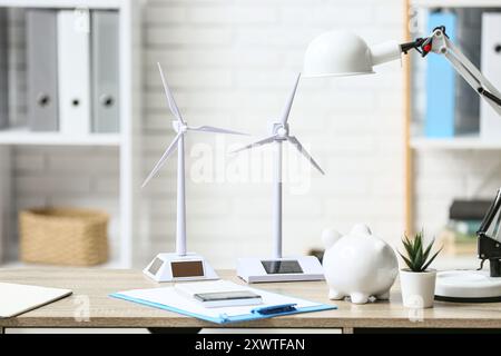 Windturbinenmodelle mit Schweinebank auf dem Tisch im Büro. Konzept der grünen Energie Stockfoto